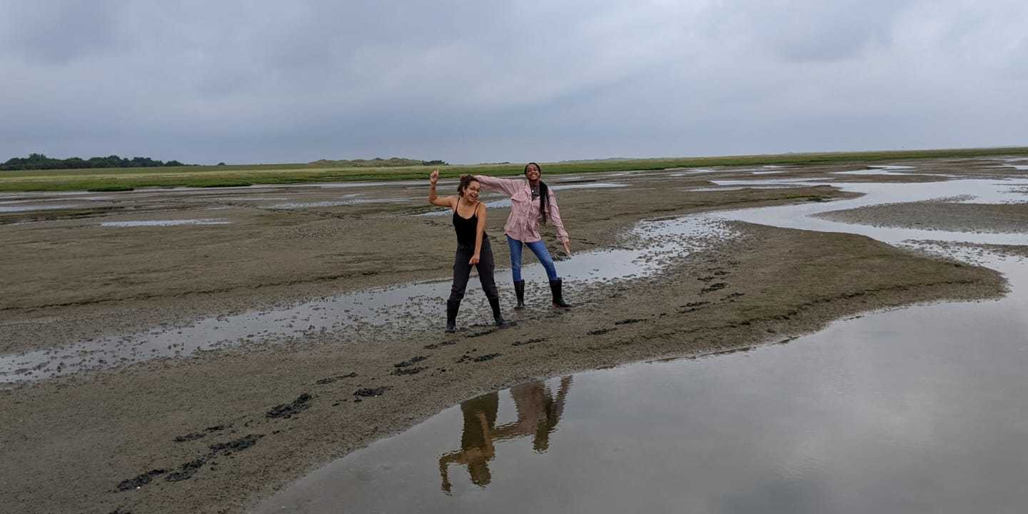Two young female researchers standing on a beach in the Wadden Sea